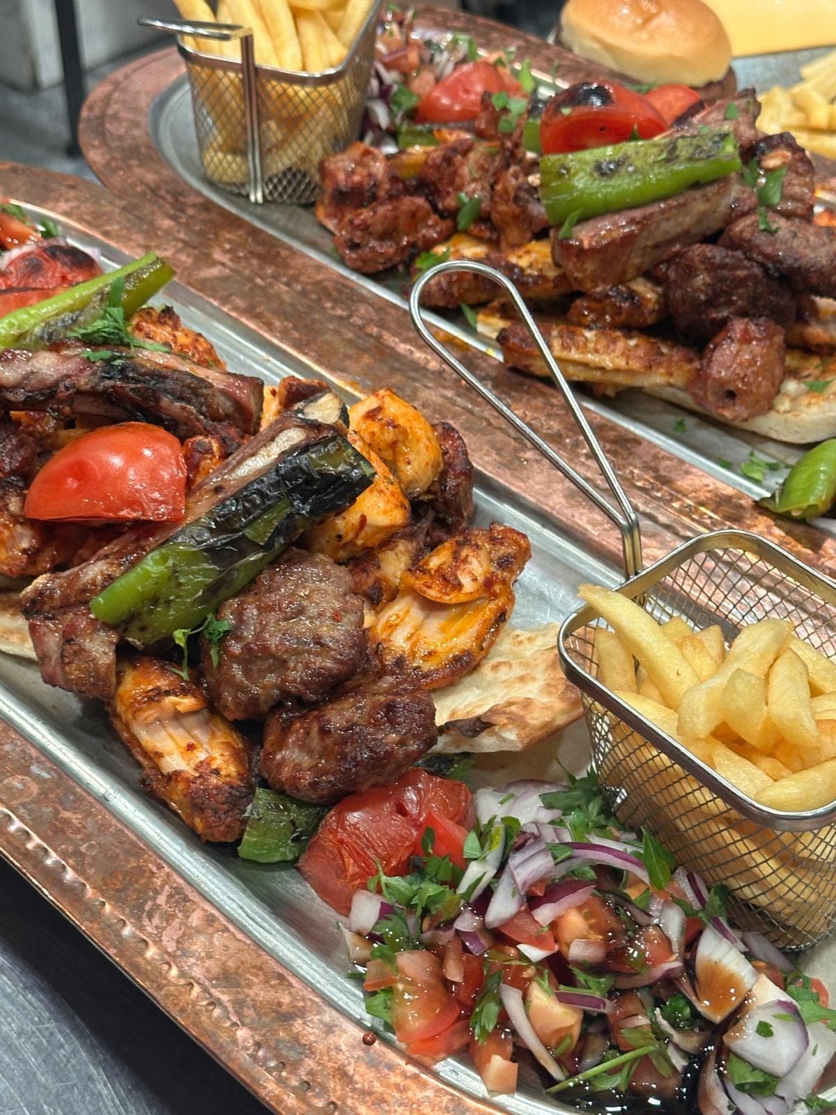 A mixed grill of kofte, lamb ribs and chicken on a hammered copper tray, with fries